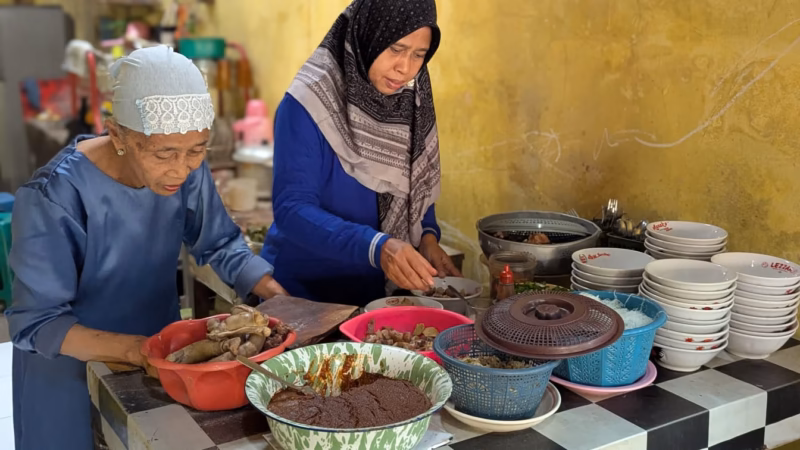 Rukiyah (73) yang karib disapa Bu Iru dibantu salah satu anak perempuannya sedang menyajikan Soto KTL kepada pelanggan di warung sederhananya yang berlokasi di Kelurahan Kauman Wiradesa, Kamis (23/4/26).