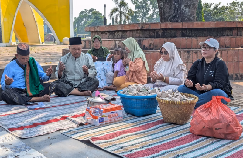 Syafi'i (kiri) khusuk berdo'a bersama anggota keluarganya sebelum melakukan aksi makan sego megono di depan Monumen Al Qur'an Alun-alun Kajen, Selasa (21/4/26).