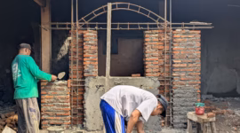 Dua pekerja sedang membangun tungku bakar tanah liat yang dilapisi dinding batu bata di lokasi TPS3R Kelurahan Medono, Minggu (17/5/26).