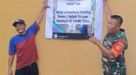 Babinsa dibantu warga memasang pemberitahuan yang bertuliskan udik-udikan tidak ada atau hoax di tembok rumah warga agar masyarakat yang terus berdatangan ke lokasi mengetahui informasi yang ada di media sosial tidak benar, Jum'at (12/6/26).