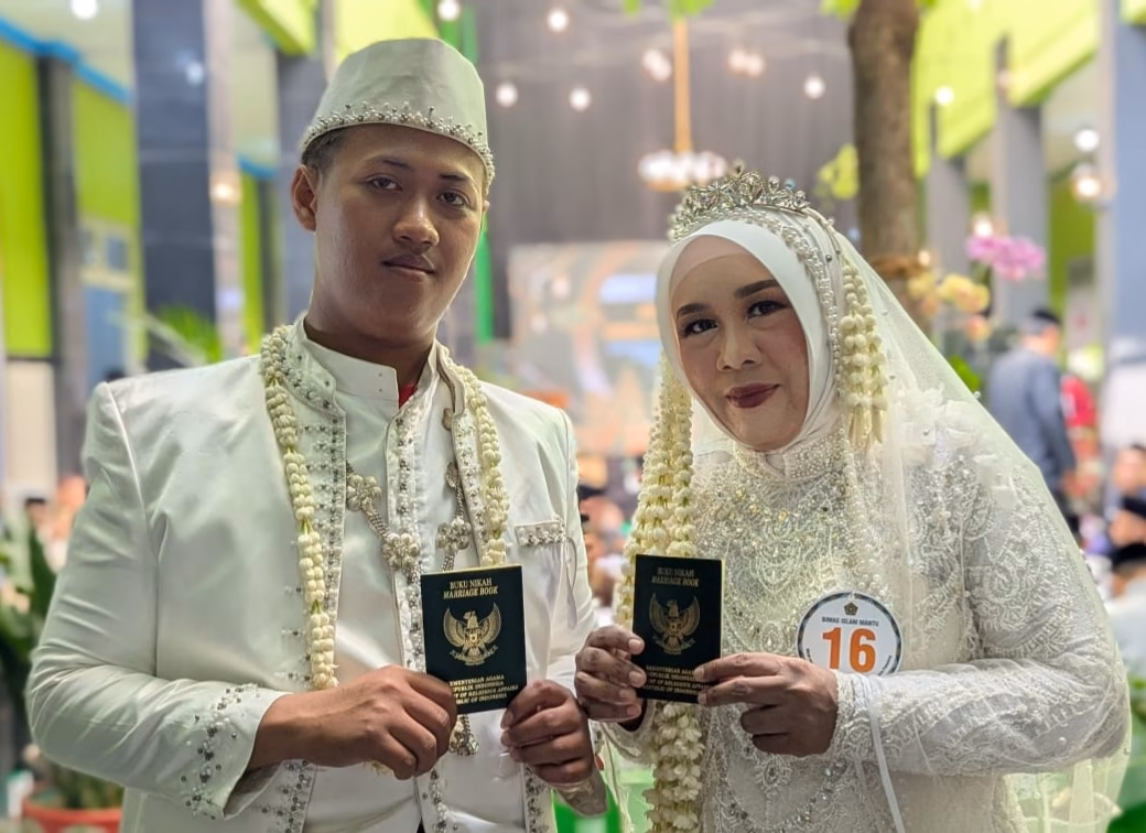 Senyum bahagia Fajri (22) dan Mutmaimah (50) setelah resmi menjadi pasangan suami istri memperlihatkan buku nikah yang menjadi bukti keteguhan cinta mereka di hadapan penghulu di Kantor Kemenag Kabupaten Pemalang, Jumat (26/6/26).