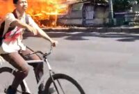 Seorang pelajar melintas di Jalan Merdeka saat kobaran api menghanguskan tiga lapak usaha milik warga di lahan eks Bioskop Merdeka, Jumat (10/7/26). Foto : Istimewa