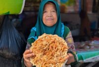 Supi'ah memperlihatkan peyek udang jumbo buatannya yang sukuran piring makan bahkan lebih besar, Selasa (21/7/26).