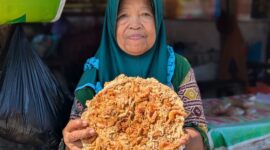Supi'ah memperlihatkan peyek udang jumbo buatannya yang sukuran piring makan bahkan lebih besar, Selasa (21/7/26).