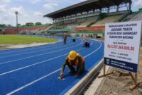 Pekerja sedang melakukan pelapisan akhir jogging track di Stadion Moh Sarengat Batang, Jumat (24/7/26). Foto : Ilustrasi AI