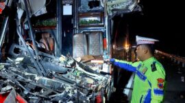 Anggota Satlantas Polres Pekalongan menunjukkan bangkai bus bagian depan yang ringsek akibat menghantam truk tronton di Tol Pemalang - Batang, Senin (27/7/26) dini hari. Foto : Istimewa