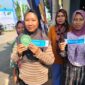 Warga Desa Siwatu yang bersebelahan dengan lokasi acara kunjungan Presiden RI Prabowo Subianto memperlihatkan kupon MBG dan undian sepeda listrik dari penyelenggara acara, Kamis (30/7/26).