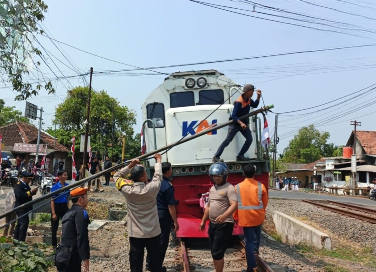 Petugas berusaha menyingkirkan tiang jaringan internet yang roboh melintang di tengah rel kereta api, Jumat (7/8/26). Foro : Istimewa