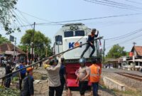 Petugas berusaha menyingkirkan tiang jaringan internet yang roboh melintang di tengah rel kereta api, Jumat (7/8/26). Foro : Istimewa