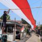 Pemuda Desa Kayugeritan sedang memasang bagian akhir dari bentangan kain merah putih sepanjang 200 meter di salah satu ruas jalan desa setempat, Sabtu (8/8/26).