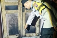 Polisi menunjukkan pintu depan rumah korban yang diduga seperti bekas dibakar dengan sengaja oleh orang tidak dikenal, Selasa (11/8/26). Foto : Istimewa