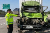 Polisi menunjukkan kondisi depan truk boks yang menabrak truk lain di depannya hingga menyebabkan pengemudinya tewas saat kejadian berlangsung, Kamis (20/8/26) pagi. Foto: Modifikasi AI