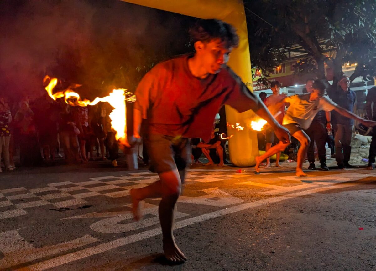 Peserta lari cepat sambil menjaga agar api tidak padam dalam lomba Estafet Obor Comal 2026 yang berlangsung di Jalan Gatot Subroto, Sabtu (22/8/26) malam.