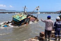 Kapal Tunda Sarden milik PT Timur Bahari kandas dan miring di kolam Dermaga Pelabuhan Niaga, Kelurahan Klidang Lor, Kabupaten Batang, setelah mengalami kebocoran yang diperparah cuaca buruk, Selasa (22/9/26). Foto: Istimewa & AI