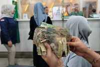 Saadah menunjukkan uang kertas miliknya yang rusak untuk ditukarkan dengan yang baru di Pegadaian Limpung, Selasa (29/9/26).