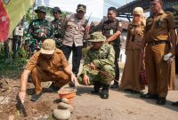 Wali Kota Pekalongan Afzan Arslan Djunaid meletakkan batu pertama pengecoran jalan di Kelurahan Pringrejo dalam kegiatan TMMD Sengkuyung Tahap IV, Selasa (13/10/26). Foto: dok Kominfo dan Ilustrasi AI
